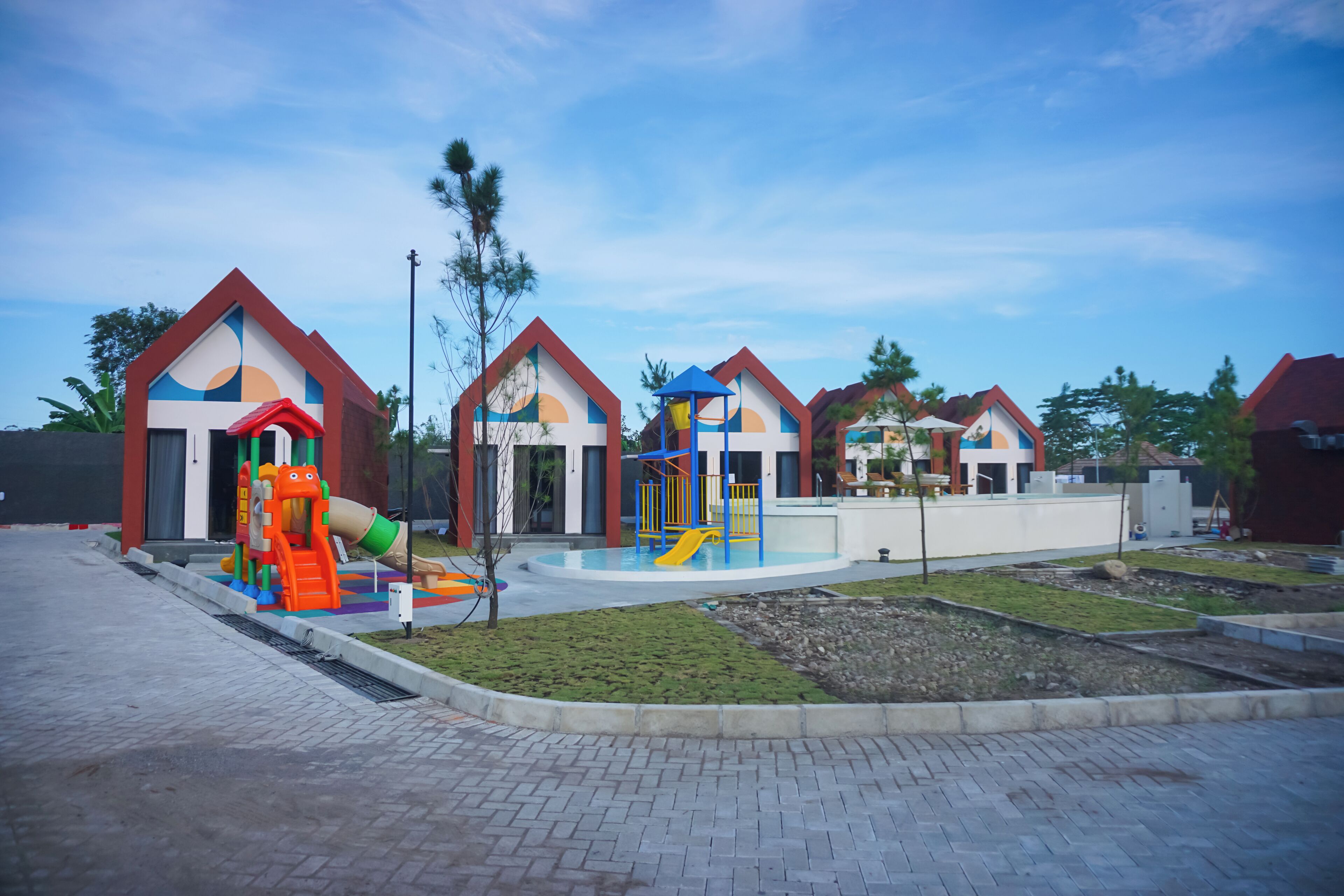Uma área de recreação infantil com estruturas de lazer coloridas e um caminho de tijolos.