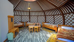A traditional yurt with four wooden beds, a central table, and a wooden bench. - Bayankhad Star Lodge (Ulaanbaatar)
