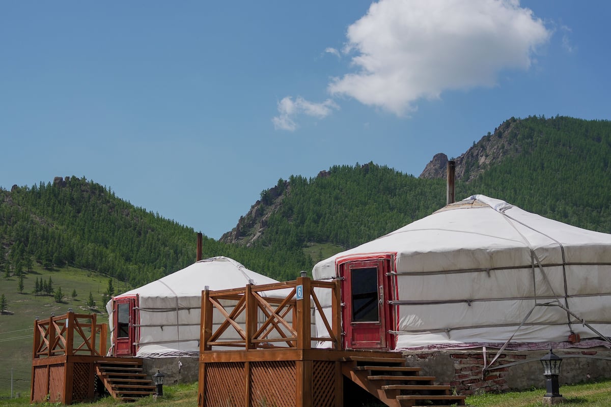 Two yurts with wooden entryways and a staircase leading up to the door.