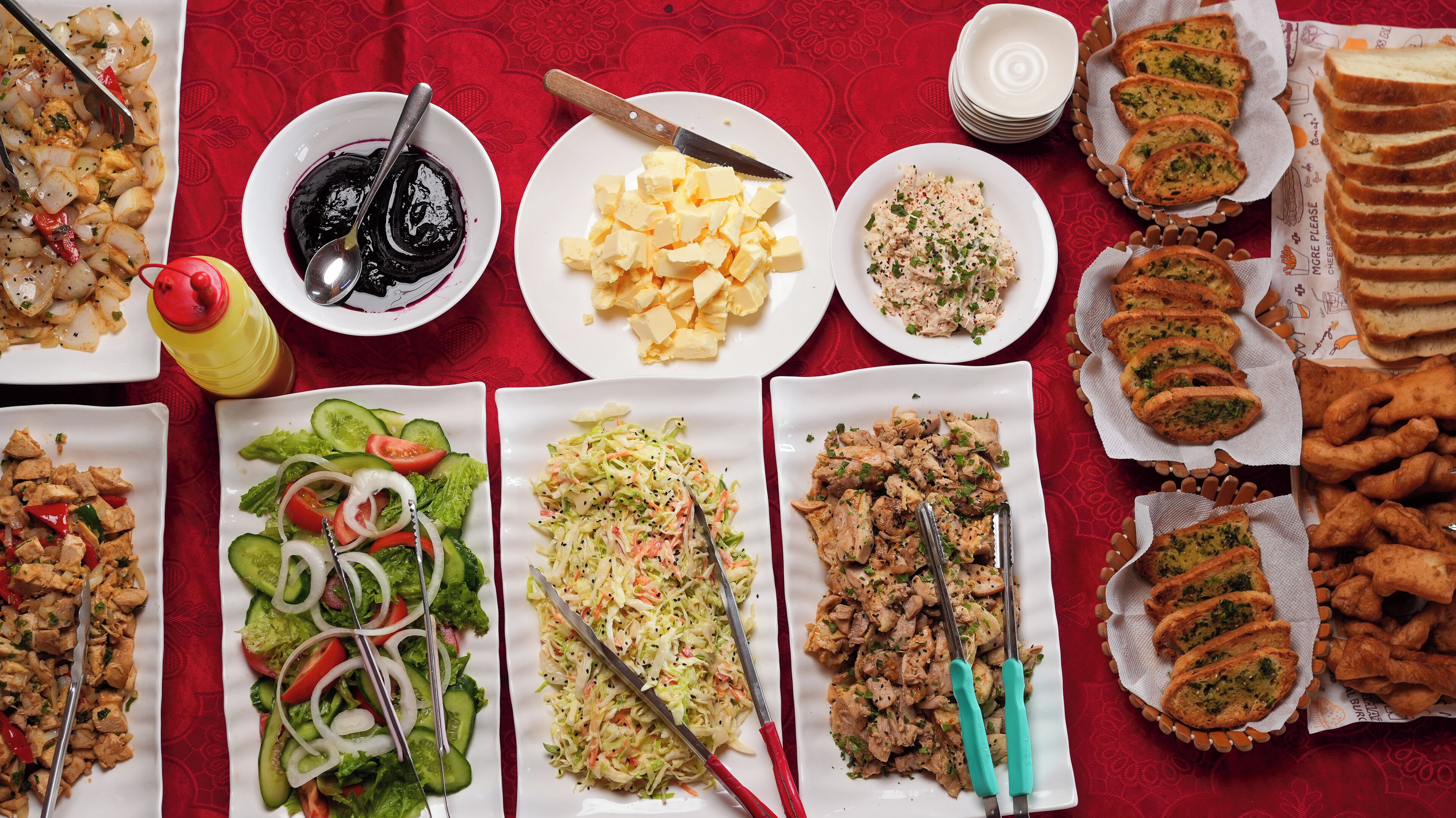 A table with various dishes including salads, meats, and bread.