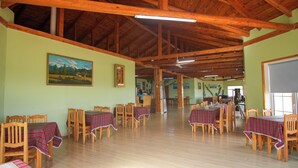A spacious dining area with wooden tables and chairs, a high wooden ceiling, and paintings on the walls. - Bayankhad Star Lodge (Ulaanbaatar)