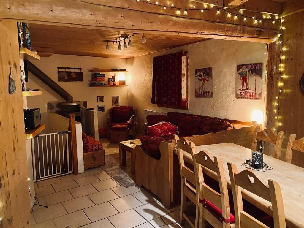 A cozy cabin interior with a wooden dining table, benches, a sofa, and a staircase.