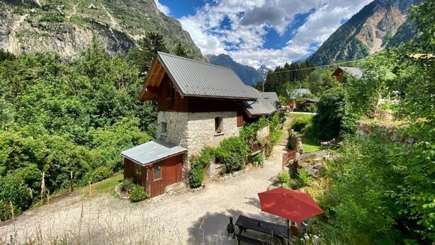 A rustic mountain lodge with a stone foundation, wooden exterior, and a metal roof. - Ecrins Lodge (Le Bourg-d'Oisans)