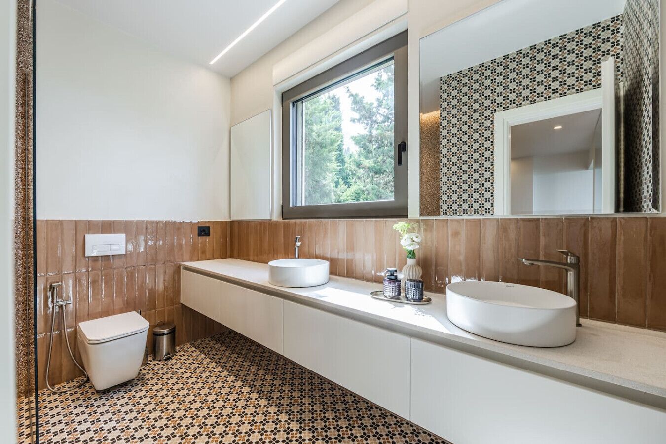 Un baño moderno con dos lavamanos, inodoro y ducha.