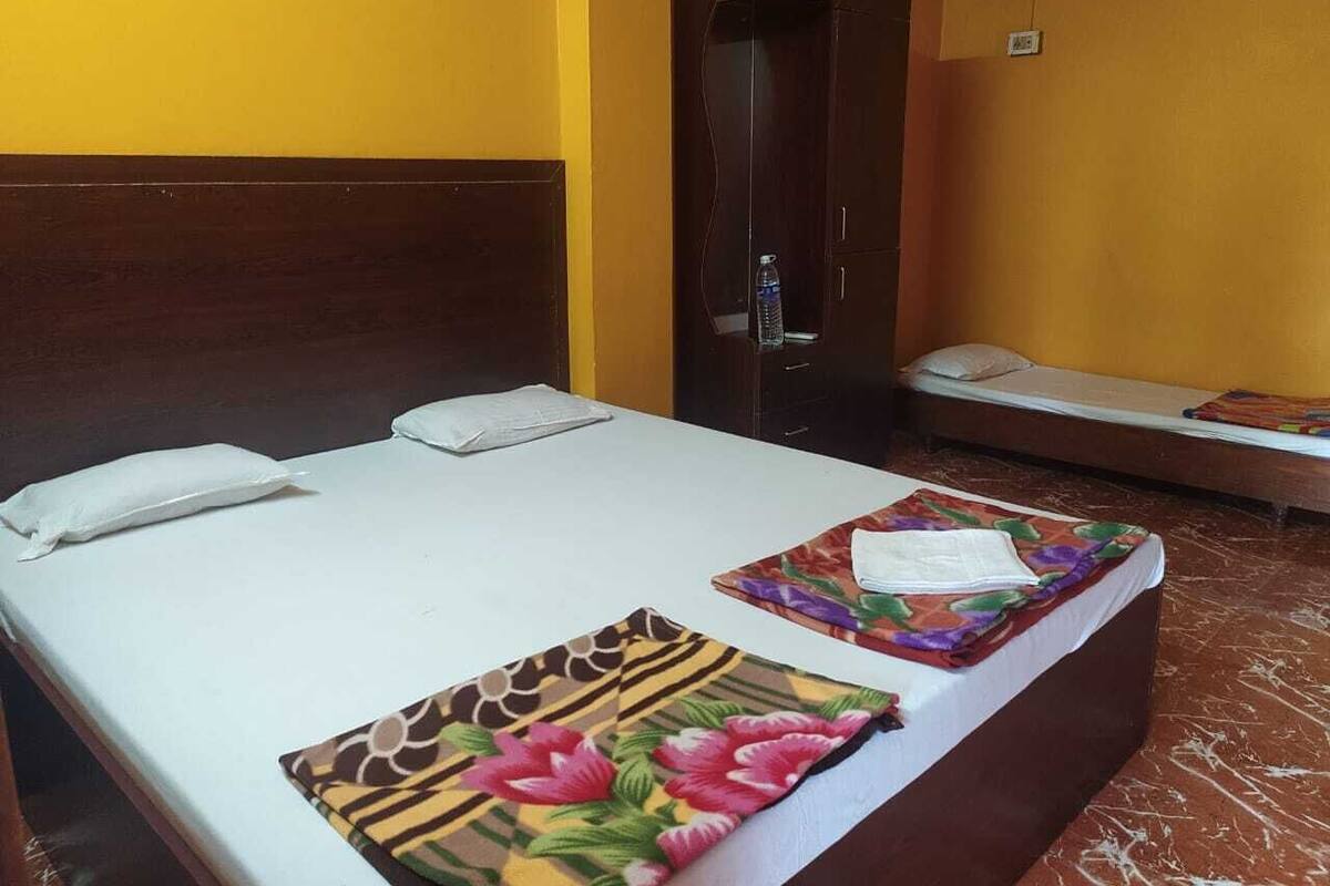A hotel room with a large bed, a smaller bed, a wardrobe, and a desk with a chair.