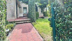 A brick pathway leading to a house with a tiled roof and a covered porch.