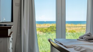 A bedroom with a large window overlooking a grassy area and a body of water.