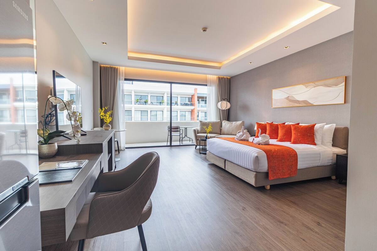 A modern hotel room with a bed, desk, chair, and a view of the city.