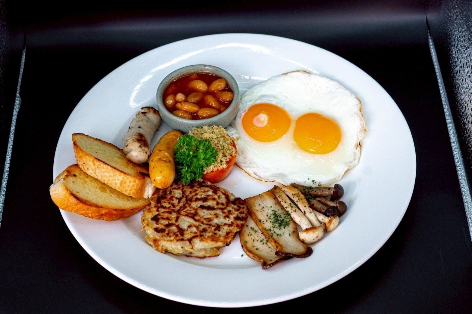 A plate of food including eggs, sausages, and potatoes.