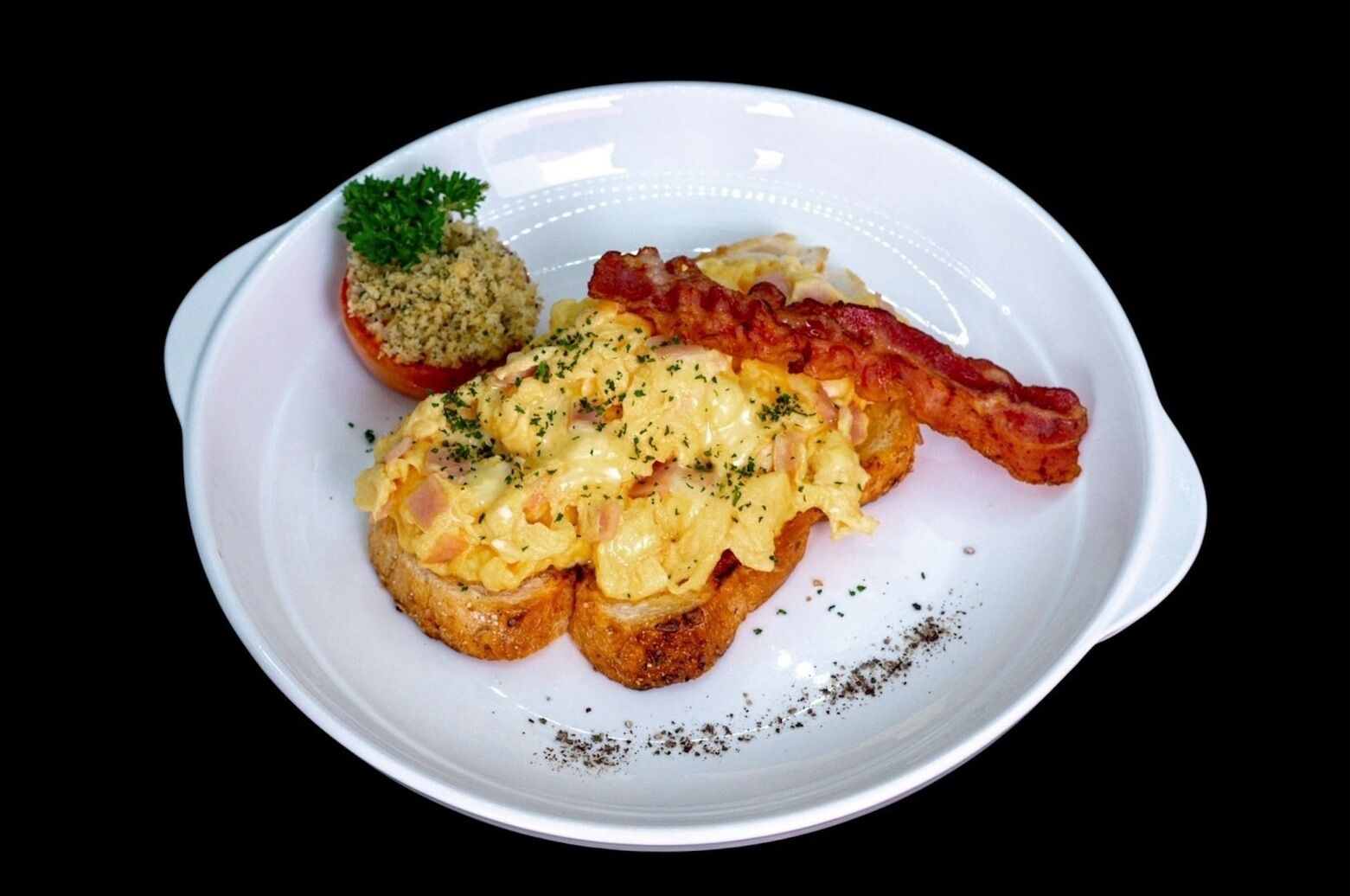 A plate with scrambled eggs, bacon, and a side of hash browns.