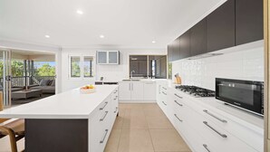 Una cocina moderna con armarios blancos, una isla grande y un horno empotrado.