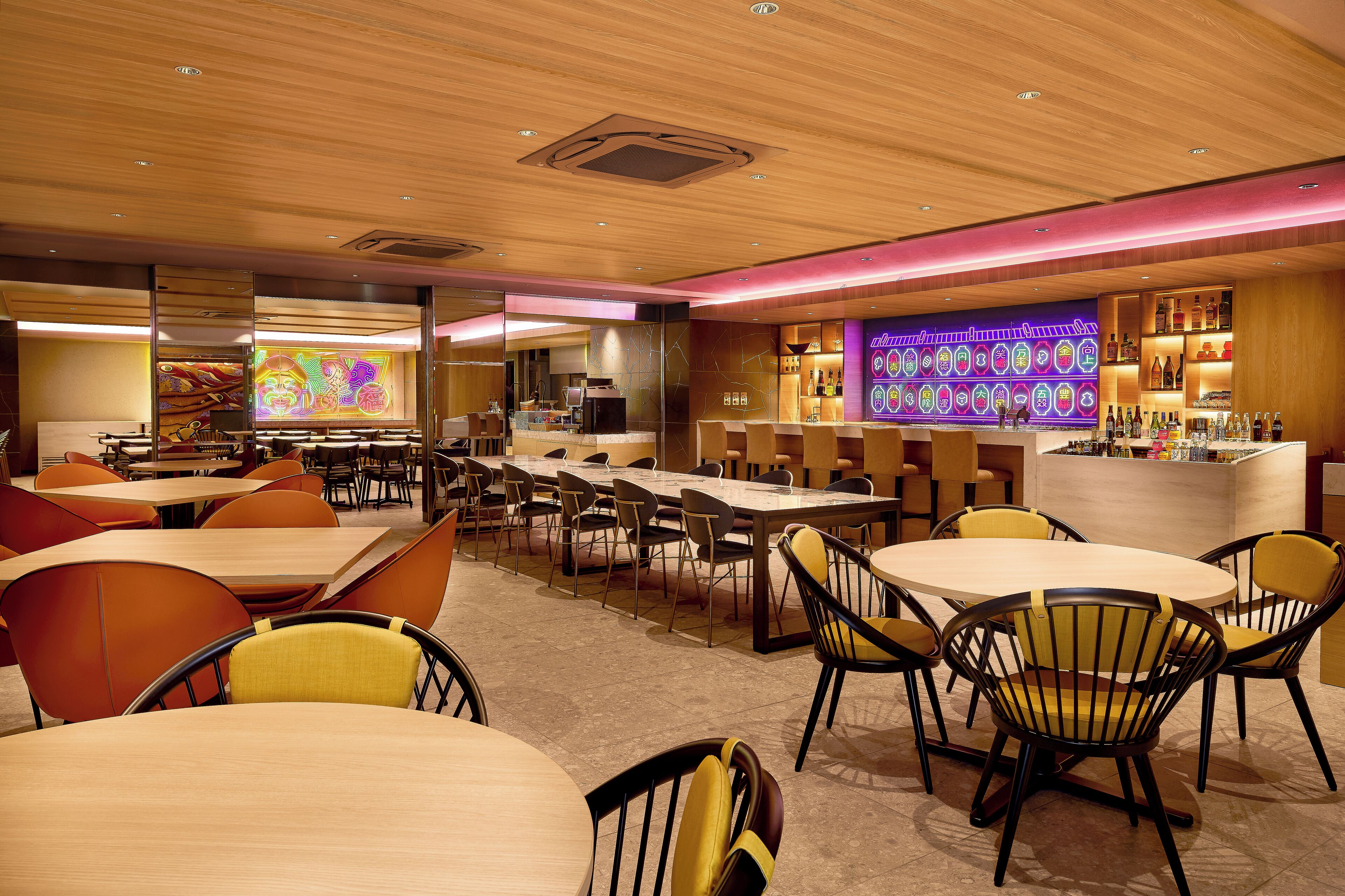 A modern restaurant with wooden ceiling, multiple dining tables, and chairs.