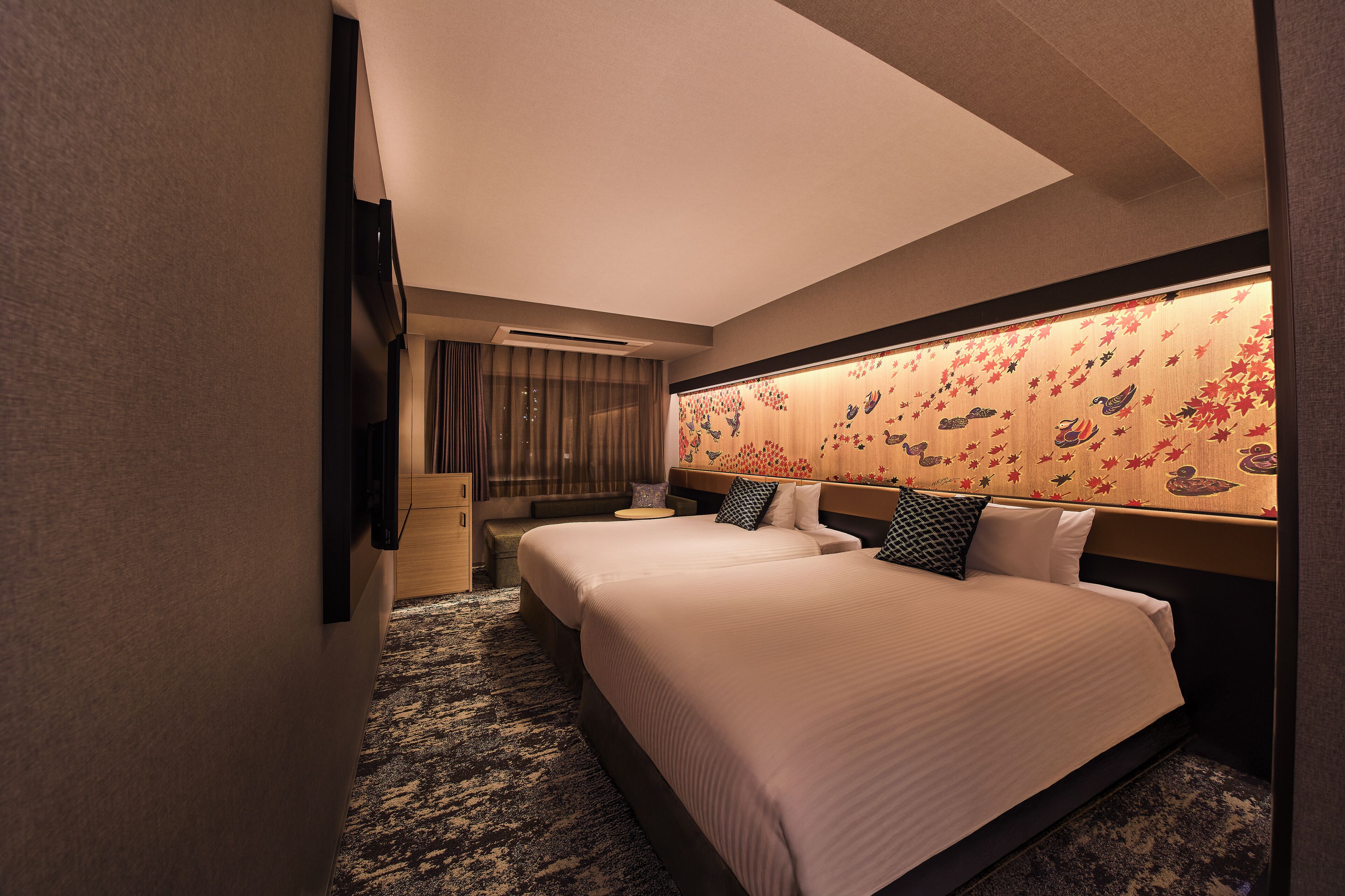 Ein Hotelzimmer mit zwei Betten, einer Couch, einem kleinen Tisch und einer Wanddeko.