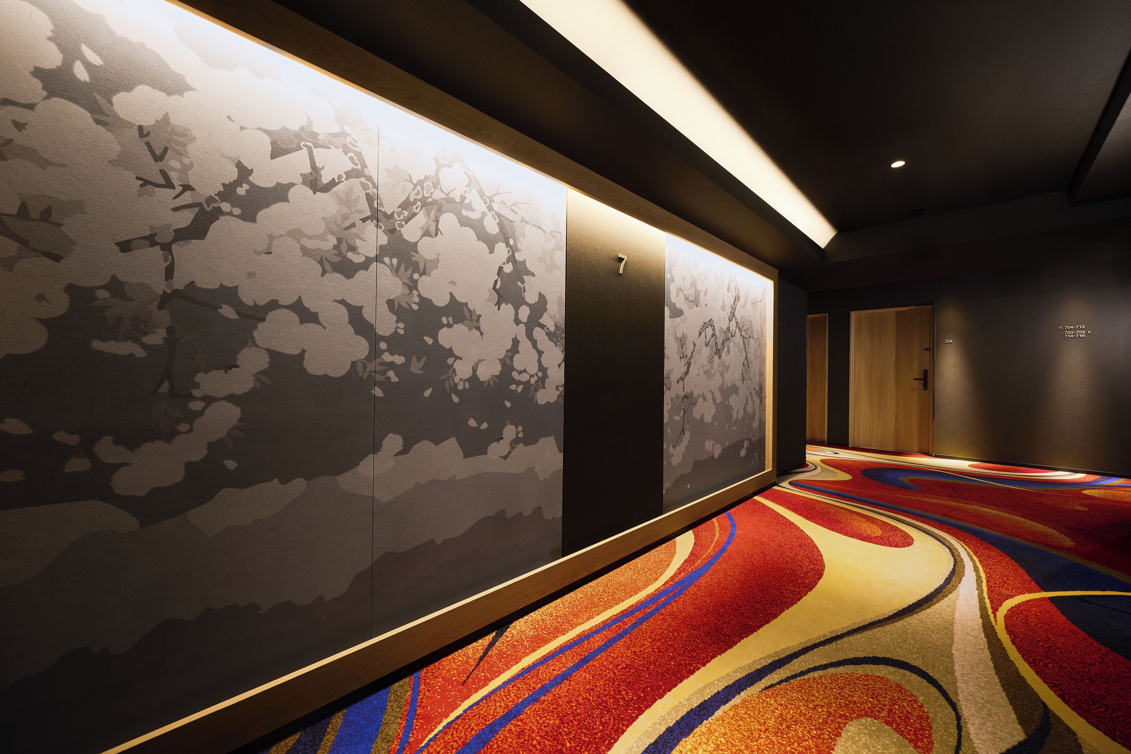 A hallway with patterned walls, a carpet with abstract designs, and a door labeled '7'.
