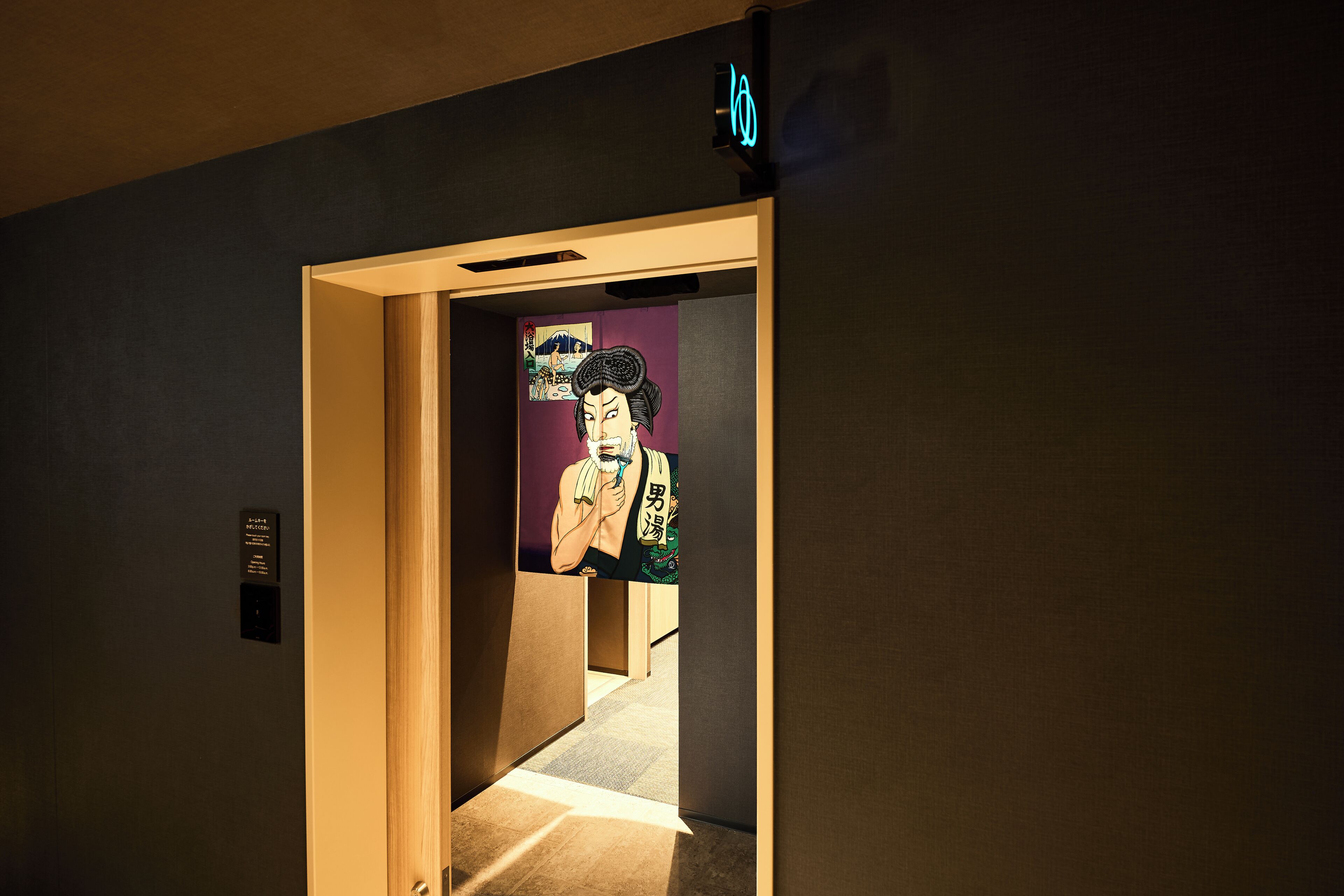 A hallway with a neon sign, a door, and a poster on the wall.