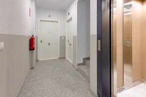 A hallway with a fire extinguisher, two doors, and an elevator.