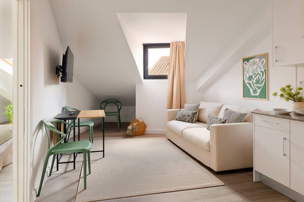 A modern loft apartment with a dining area, a sofa, and a kitchen.