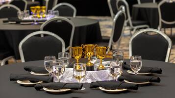 A banquet table set with glasses, plates, and golden trophies.