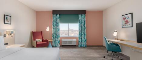 Une chambre d’hôtel équipée d’un lit, d’un bureau, d’une chaise, d’un appareil de climatisation et d’une fenêtre avec des rideaux.