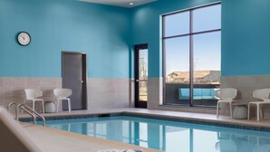 Una piscina interior con paredes azul claro, una puerta y dos sillas blancas.
