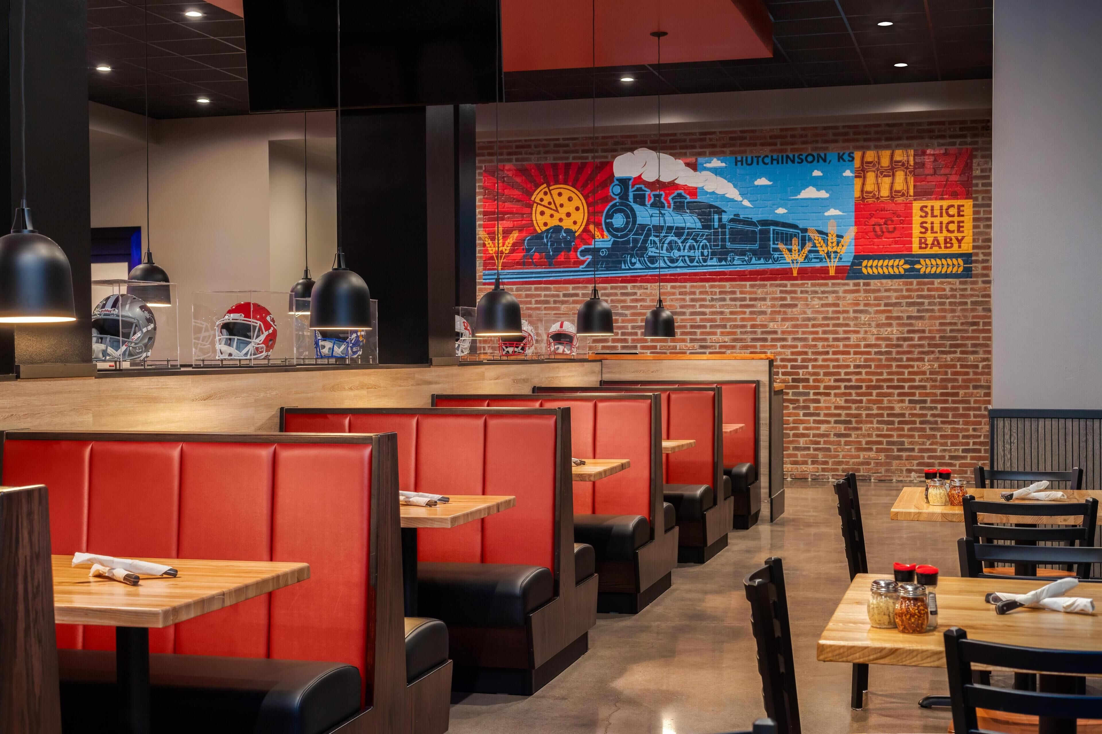 A restaurant interior with booths, tables, and a mural on the wall.
