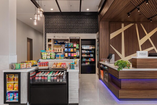 A hotel lobby with a reception desk, a minibar, snack display, and a beverage cooler.