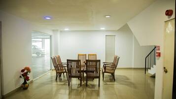 A spacious room with a dining table and chairs, a vase with flowers, and a staircase leading to another floor.