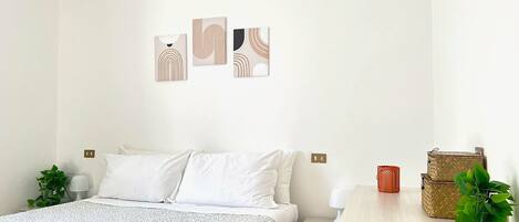 A minimalist bedroom with a bed, bedside tables, and wall art.