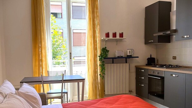 Una habitación de hotel compacta con cama, una pequeña mesa de comedor y una kitchenette.