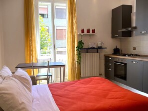 Une chambre d’hôtel de taille réduite, comprenant un lit, une petite table à manger et une kitchenette.