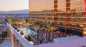 A high-rise hotel with a rooftop pool, palm trees, and a view of the cityscape. - Trump Condo Hotel in Vegas (Las Vegas)