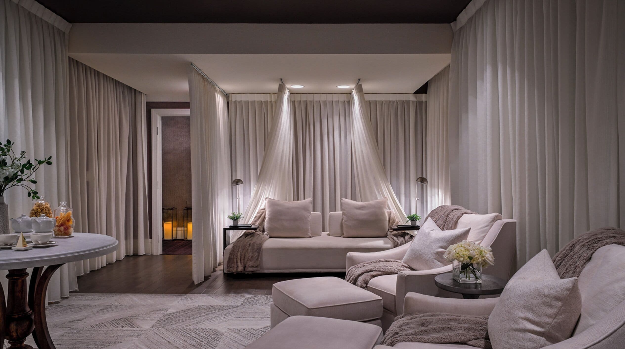 Een moderne, elegant ingerichte slaapkamer met een groot bed, twee slaapbanken, een ronde tafel en een decoratieve vaas.