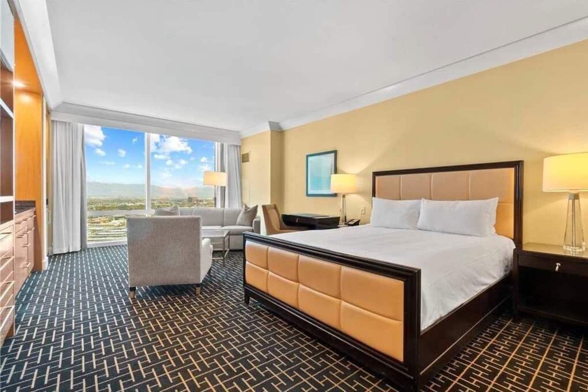 Habitación de hotel con una cama grande, un escritorio, una silla y vistas a la ciudad.