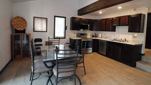 Una cocina moderna con armarios de madera oscura, electrodomésticos de acero inoxidable y una mesa de comedor de vidrio con sillas.