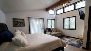 Un dormitorio con una cama grande, una silla, un escritorio y una ventana.