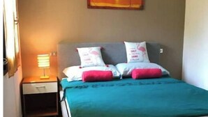 A bedroom with a bed, a nightstand, a lamp, and a painting on the wall.
