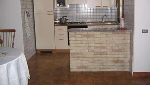 A kitchen with white cabinets, a brick island, and a tiled backsplash.