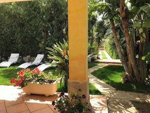 A garden area with a pathway, a yellow column, and a row of white lounge chairs. - Villa Cristina (Sardegna)