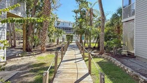 A wooden pathway leading to a building surrounded by trees.