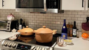 A kitchen with a stainless steel microwave, a stove with a digital clock, and various kitchen items on the counter.