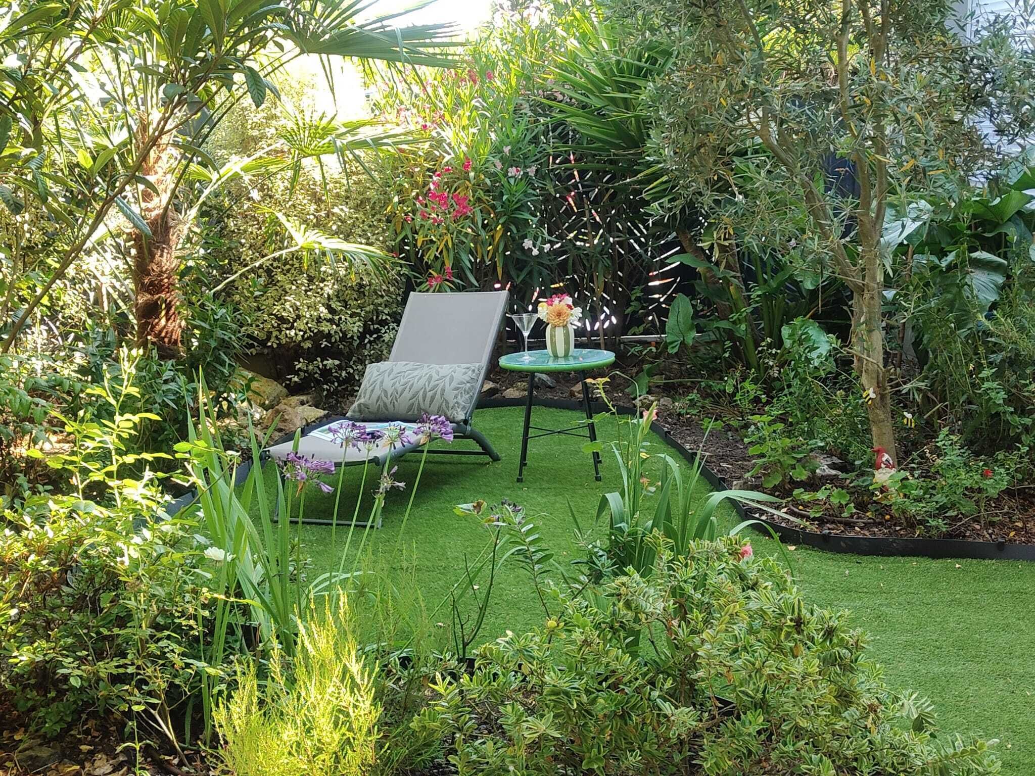 A garden with a lawn, a chair, and a table with flowers.