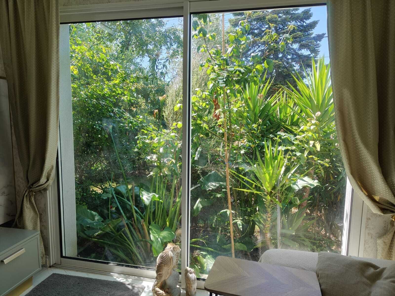 Ein Zimmer mit einer Schiebeglastür, die zu einem üppigen Garten führt.