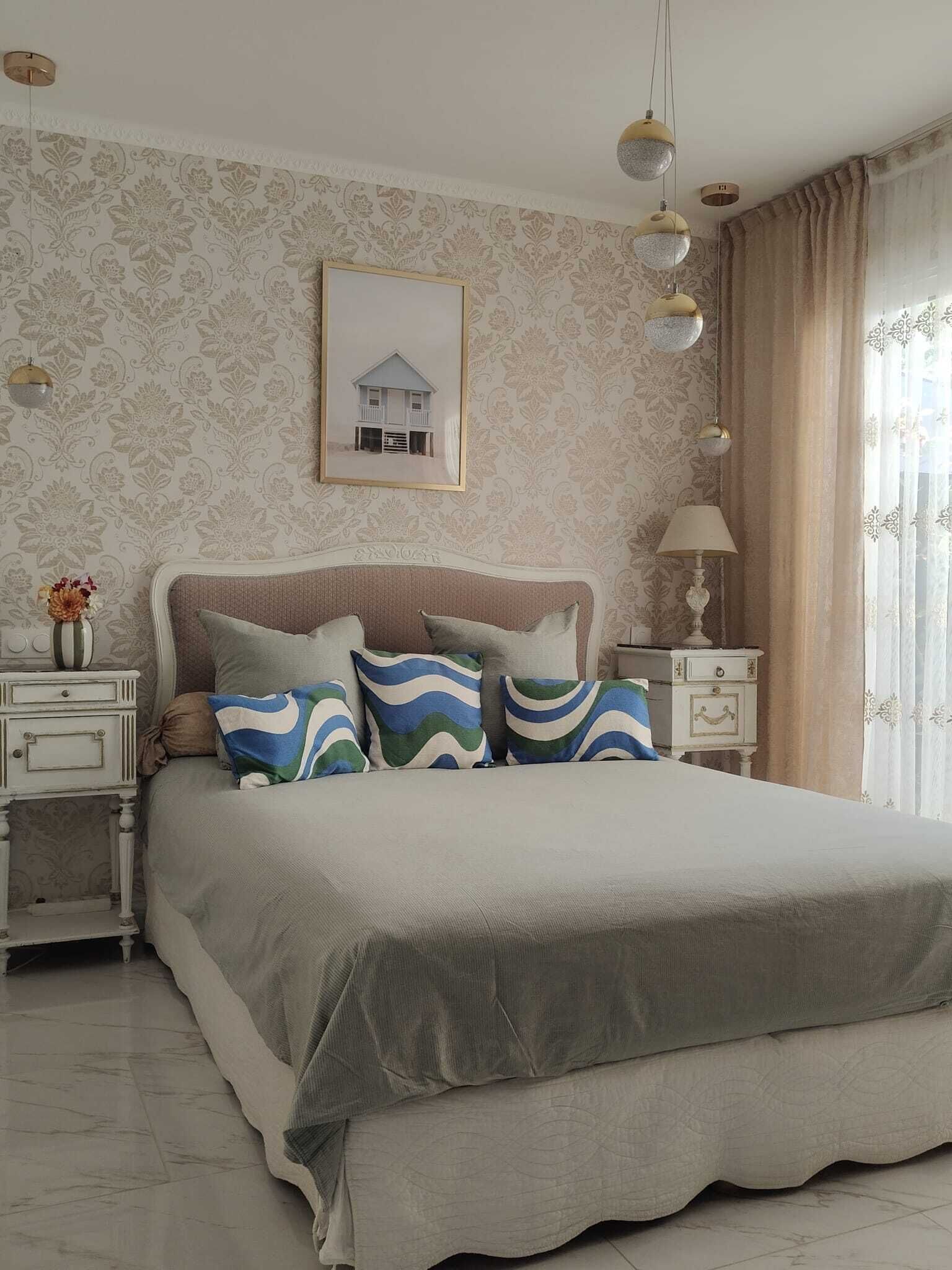 Ein Schlafzimmer mit einem großen Bett, Nachttischen, einem gerahmten Bild und einer Lampe.