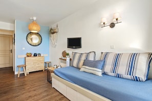 Une chambre à coucher comprenant un lit, une télévision, une commode, un bureau et un luminaire suspendu.