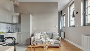 A spacious living area with a sofa, coffee table, and kitchen in the background. - Browar Hevelius Apartments by GA (Gdańsk)
