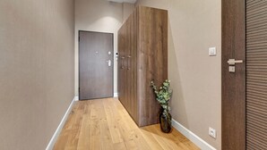 A hallway with wooden flooring, a wooden wardrobe, and a door with a handle. - Browar Hevelius Apartments by GA (Gdańsk)