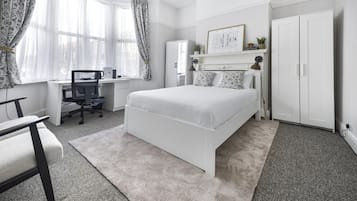 A bedroom with a bed, a desk, and a wardrobe.