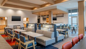 A modern restaurant with booths and tables, a kitchen area, and a large window. - Hyatt House Fresno Campus Pointe (Fresno)
