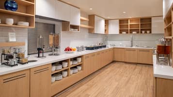 A modern kitchen with wooden cabinets, white countertops, and a variety of food items and utensils.