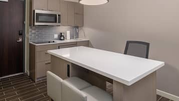 Une cuisine moderne dotée d’un îlot central, d’un four à micro-ondes, d’un évier et d’une chaise.